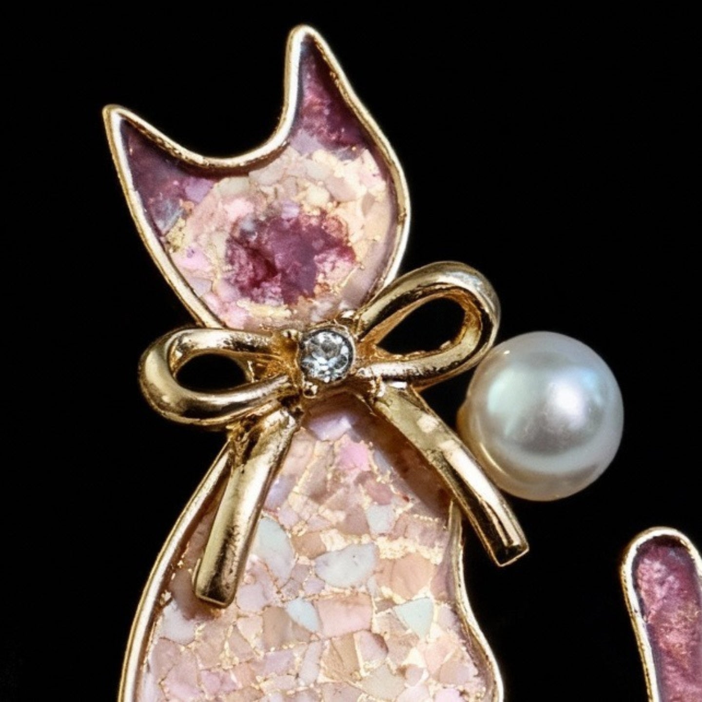 Close-up of handcrafted mother of pearl nacre shell brooch inlay on cat brooch showing pink-blue gradient