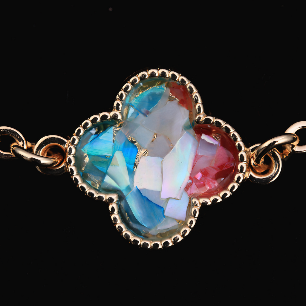 Close-up of gradient pink-blue mother of pearl clover pendant on gold bracelet