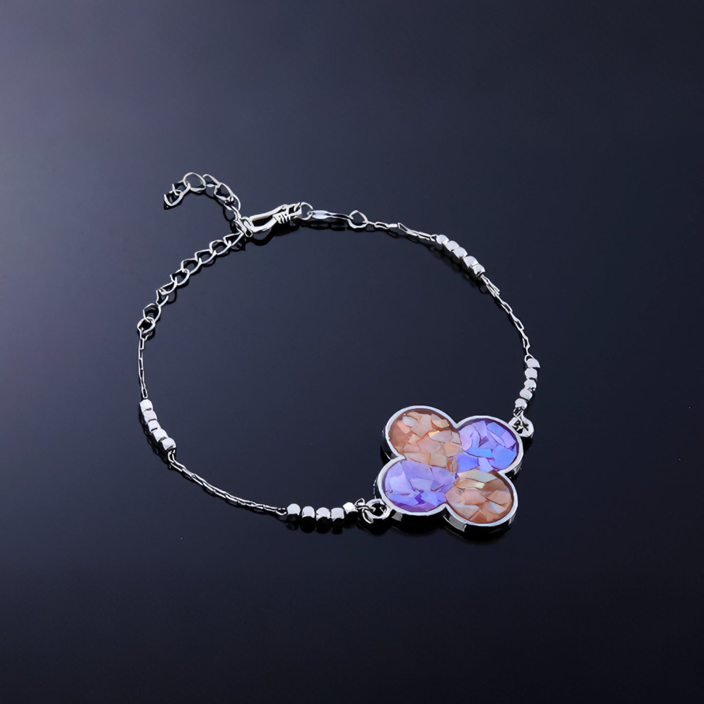 Close-up of clover charm with hand-placed blue purple mother-of-pearl fragments  