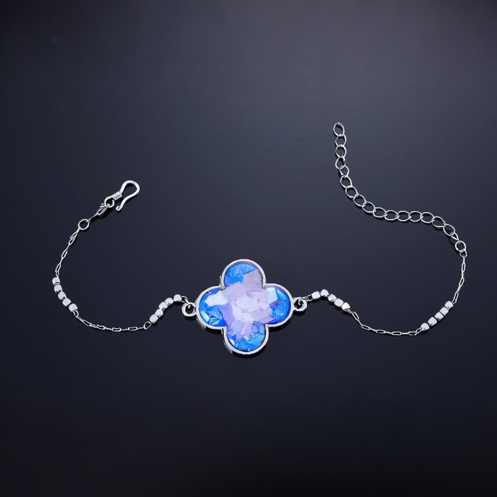 Close-up of clover charm with hand-placed blue purple mother-of-pearl fragments  