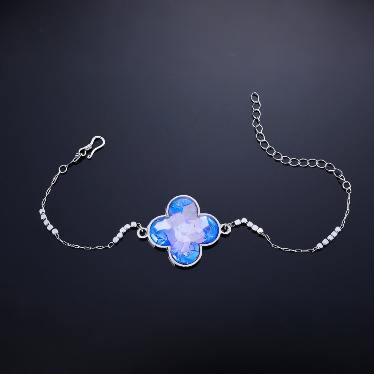 Close-up of clover charm with hand-placed blue purple mother-of-pearl fragments  